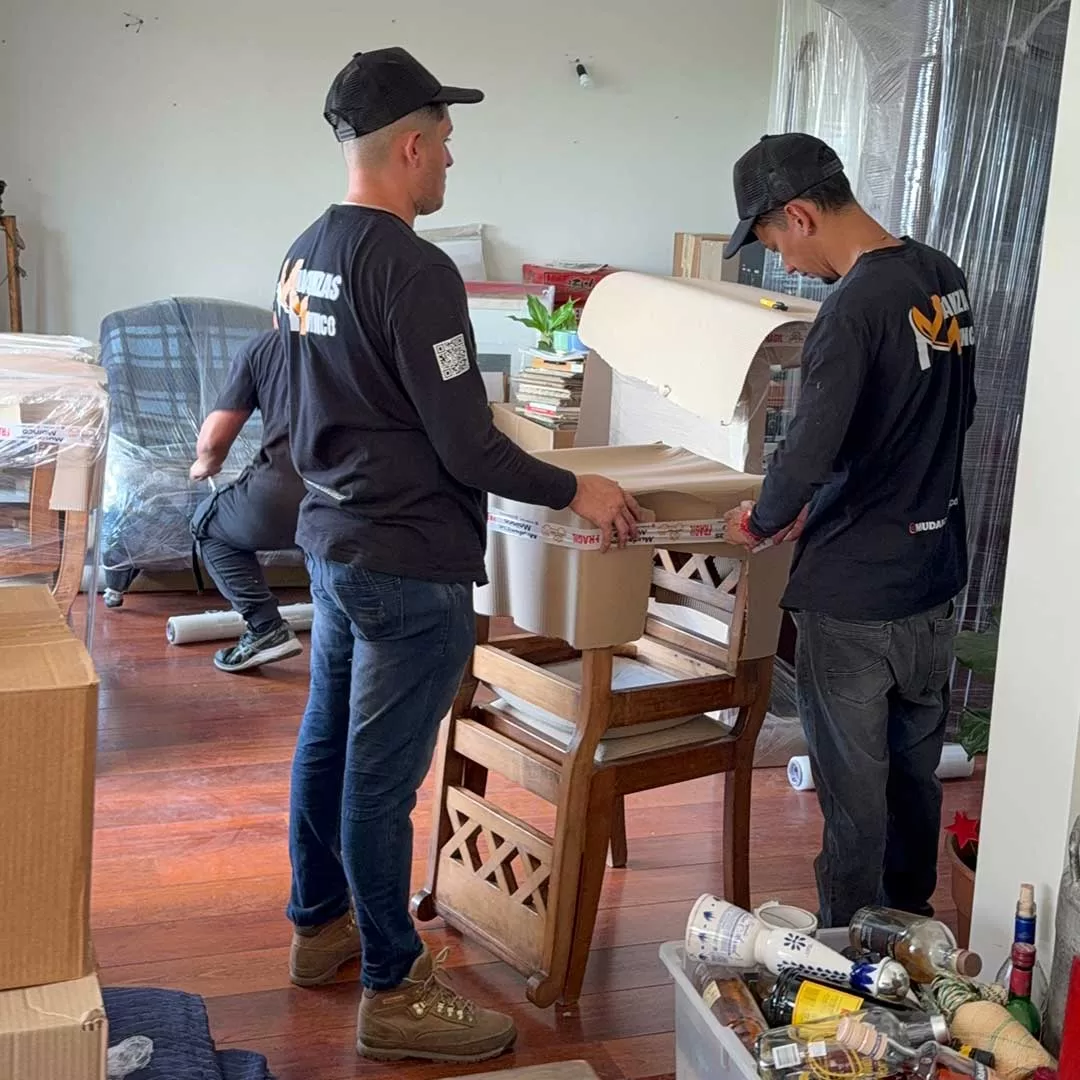 Dos trabajadores de Moinco embalando muebles con film
